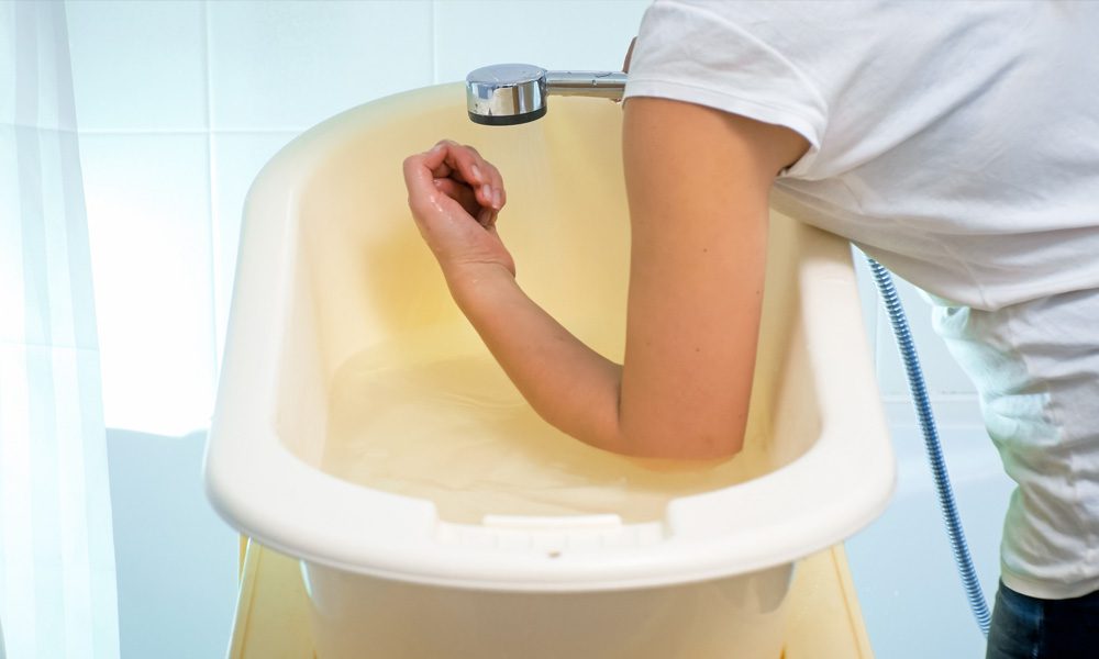Testing bathwater temperature with the forearm to prevent scalds in children.